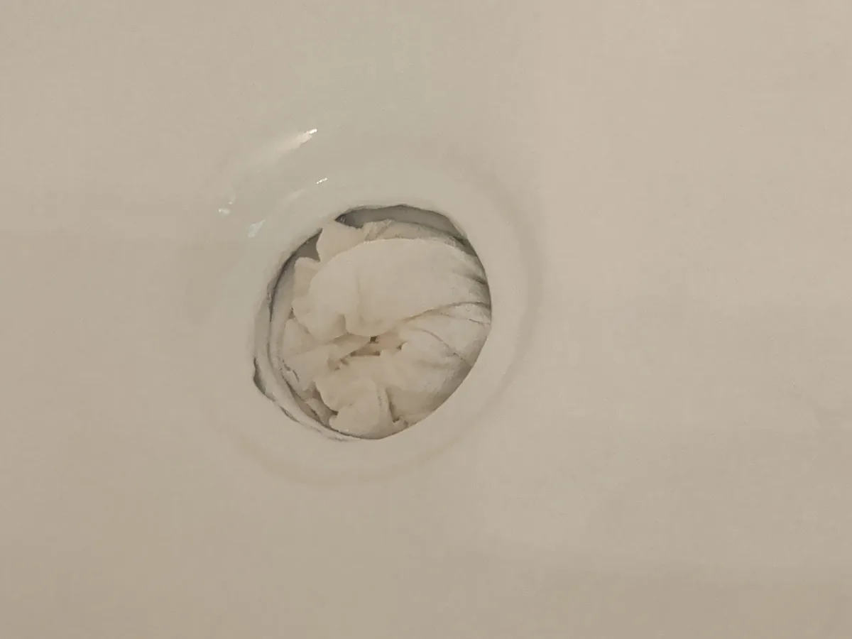 Damaged opening around a bathtub drain before repair in Garland, Texas